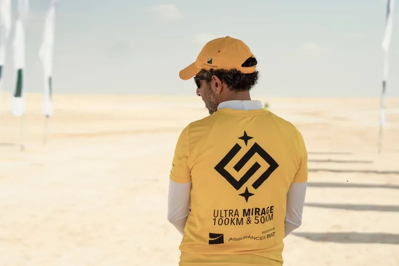 A race organizer, seen from behind, facing the white expanse of the course.