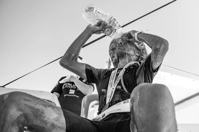 At the finish, an exhausted runner pours a bottle of water over his face.